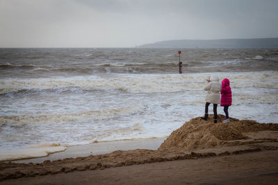 Rear view of couple on beach against sea