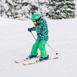 Full length of boy skiing on snow covered land