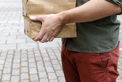 Midsection of man holding boxes on street