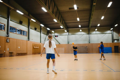 Female friends playing handball in sports court