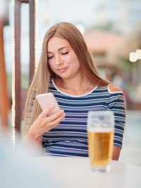 Portrait of woman drinking beer at beach cafe