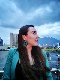 Portrait of beautiful woman in city against sky