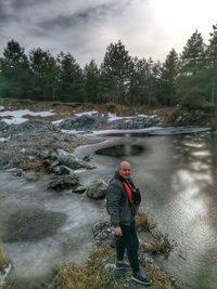 Man standing on riverbank against sky