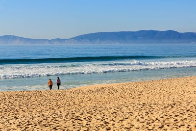 People at beach against sky