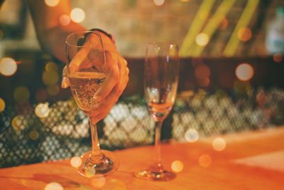 Cropped hand of woman holding champagne flute on table