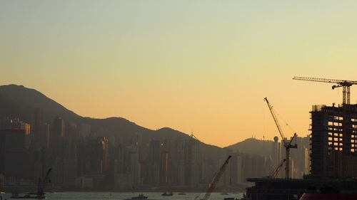 Silhouette of construction site against sky during sunset