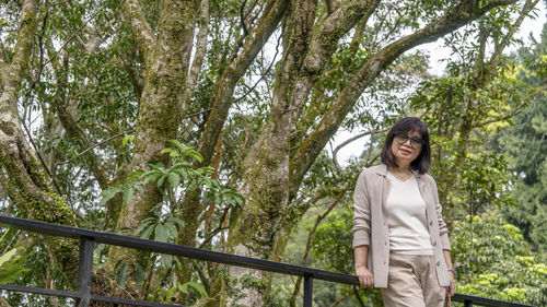 Smiling young woman standing against trees