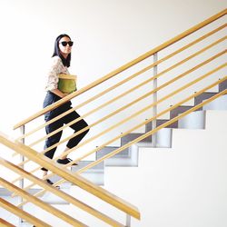 Portrait of woman in sunglasses walking on steps by wall