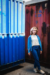 Portrait of woman standing against cargo container