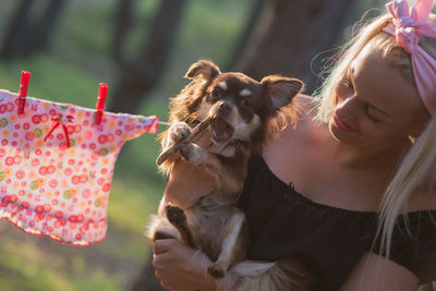 Close-up of smiling woman carrying chihuahua