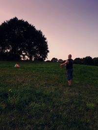 Full length of man standing on field against sky during sunset