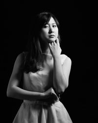 Beautiful young woman standing against black background