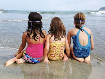 Rear view of girls sitting on beach