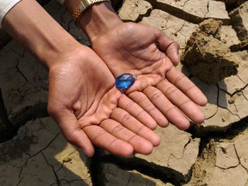 Cropped hands of woman holding blue diamond over ground