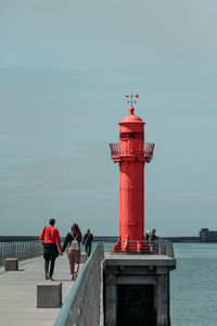 Couple walking on pier against sky