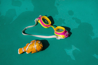 High angle view of swimming goggles and toy fish on table