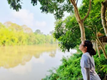 Woman standing by lake against sky