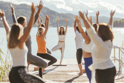 Female instructor teaching vrikshasana to men and women during yoga class