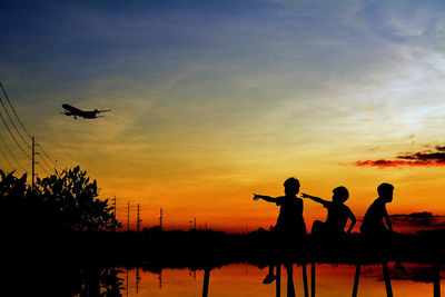 Silhouette men by tree against sky during sunset