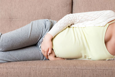 Midsection of woman sitting on sofa