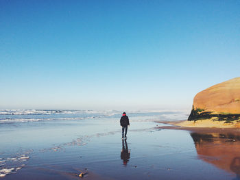 Man standing on wet beach against sky