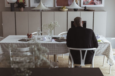 Rear view of businessman working on laptop in living room