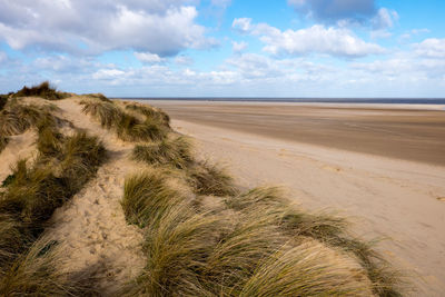 Scenic view of sand dunes against cloudy sky