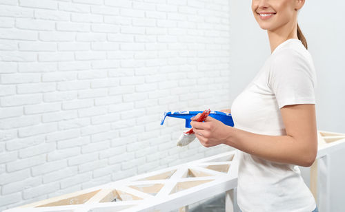 Side view of young woman standing against white wall