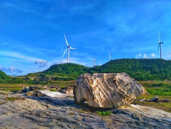 Windmills on landscape against blue sky