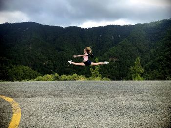 Side view of woman doing split in mid-air