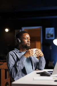 Side view of man using mobile phone while sitting in cafe