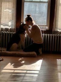 Young woman sitting with cat on hardwood floor