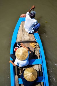 High angle view of men sitting in boat over lake