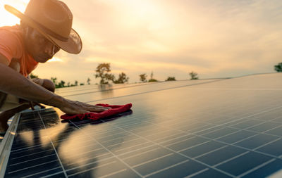 Man cleaning solar panel on roof. solar panel or photovoltaic module maintenance. sustainable