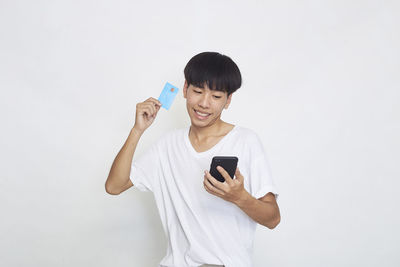 Smiling young man using mobile phone against white background