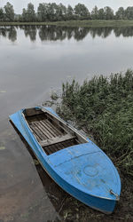 Blue boat in a big river among green forest
