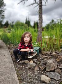 Portrait of young child sitting on rock