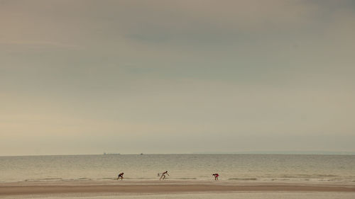 People at beach against sky
