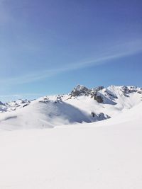 Scenic view of snowcapped mountains against blue sky