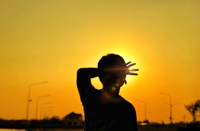 Silhouette man standing against orange sky during sunset