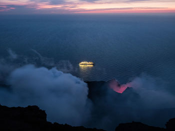 Active vulcano and cruise ship at sunset