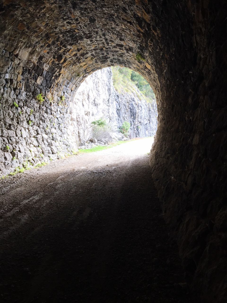 the way forward, arch, road, transportation, tunnel, indoors, built structure, wall - building feature, architecture, passing, archway, empty road, day, light at the end of the tunnel, mountain, long, light at the end of tunnel, arched, no people, surface level, non-urban scene, diminishing perspective