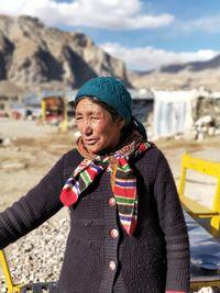 Senior woman standing against sky