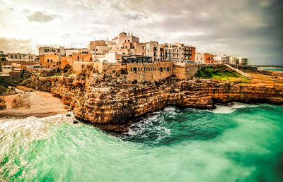 Buildings by sea against sky in city