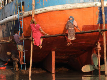 Women workers painting a ship in dockyard