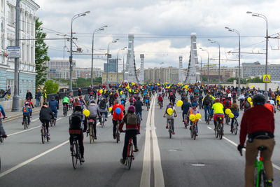 Rear view of people riding bicycles on road in city