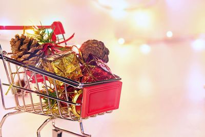 Close-up of gifts and pine cones in small shopping cart on table
