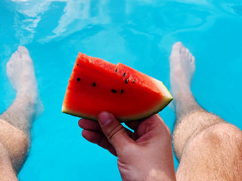 Midsection of man holding ice cream in swimming pool