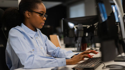 Side view of man using laptop while sitting in office