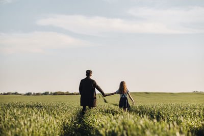 Couple standing on field against sky